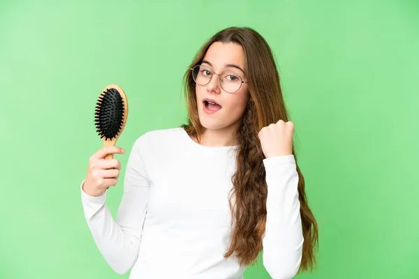 Teenager girl with hair comb over isolated chroma key background celebrating a victory