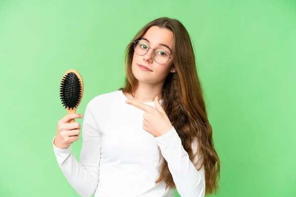 Teenager girl with hair comb over isolated chroma key background and pointing it