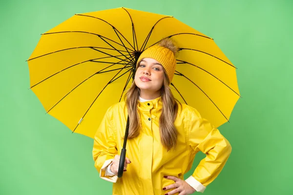 若いです女の子とともにレインプルーフコートと傘上の隔離されたクロマキーバックポーズアームとともに尻と笑顔 — ストック写真