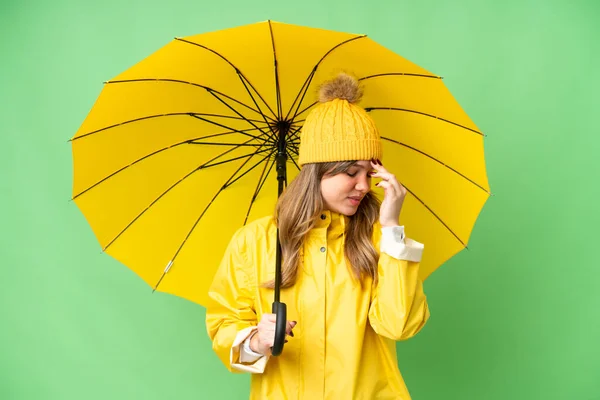 穿着防雨外套和雨伞的小女孩在孤零零的色彩斑斓的背景上大笑 — 图库照片