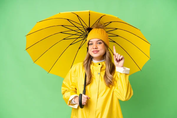若いです女の子とともにレインプルーフコートと傘上の隔離されたクロマキー背景指摘素晴らしいですアイデア — ストック写真