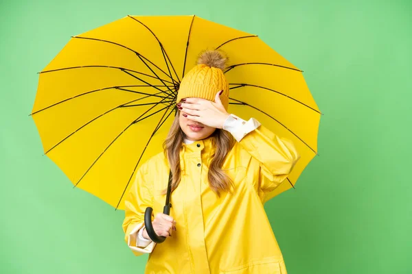 隔離されたクロマキーの背景にレインプルーフコートと傘を手で目をカバーした若い女の子 何か見たくない — ストック写真