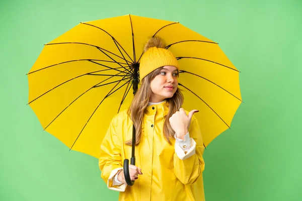Молодая Девушка Непромокаемым Пальто Зонтиком Изолированном Фоне Хрома Ключ Указывая — стоковое фото