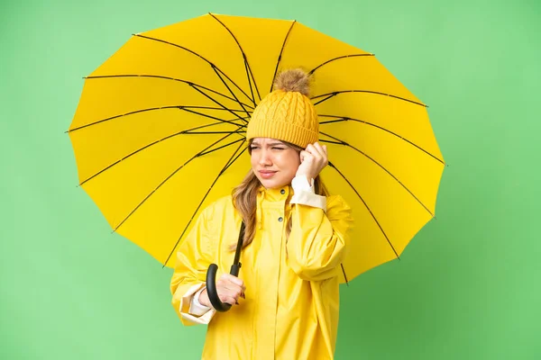 穿着防雨外套 披着雨伞 披着孤立的彩色关键背景的小女孩灰心丧气 耳朵被蒙住了 — 图库照片