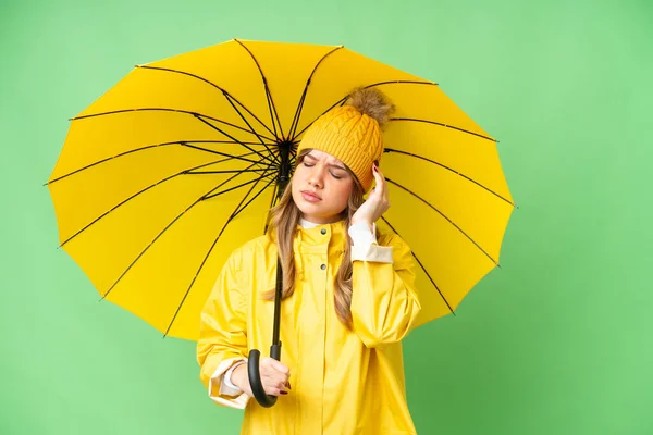 穿着防雨外套和雨伞的年轻女孩有头疼的孤立的色斑背景 — 图库照片