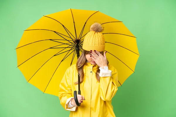 若いです女の子とともにレインプルーフコートと傘上の隔離されたクロマキー背景とともに疲れと病気表現 — ストック写真