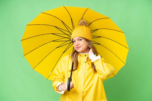 穿着防雨外套和雨伞的小女孩在孤零零的色彩斑斓的背景上大笑 — 图库照片