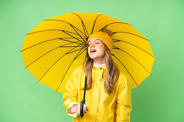 若いです女の子とともにレインプルーフコートと傘上の隔離されたクロマキー背景笑い — ストック写真