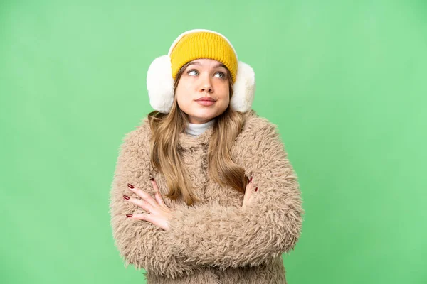 年轻姑娘披着冬衣 披着孤立的彩色关键背景 提起肩膀时做了个怀疑的手势 — 图库照片