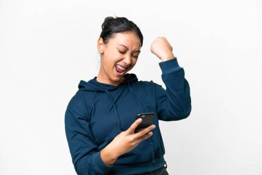 Genç Uruguaylı kadın izole edilmiş beyaz arka planda telefon zafer pozisyonunda.