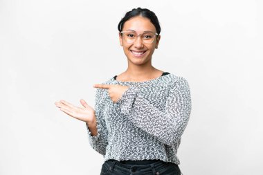 Young Uruguayan woman over isolated white background holding copyspace imaginary on the palm to insert an ad
