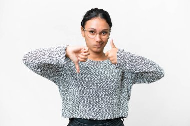 Young Uruguayan woman over isolated white background making good-bad sign. Undecided between yes or not