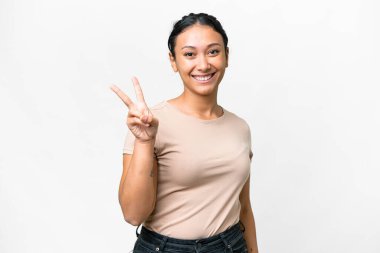 Genç Uruguaylı kadın izole edilmiş beyaz arka planda gülümsüyor ve zafer işareti gösteriyor.