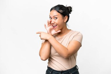 Young Uruguayan woman over isolated white background pointing to the side to present a product and whispering something