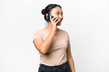 Genç Uruguaylı kadın izole edilmiş beyaz arka planda cep telefonuyla sohbet ediyor.
