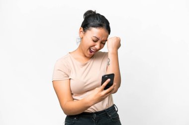 Genç Uruguaylı kadın izole edilmiş beyaz arka planda telefon zafer pozisyonunda.