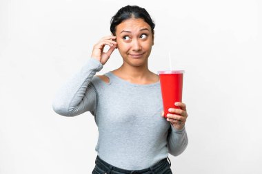 Young Uruguayan woman holding soda over isolated white background having doubts and with confuse face expression