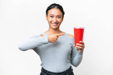 Genç Uruguaylı kadın izole edilmiş beyaz arka planda soda tutuyor ve ona doğrultuyor.