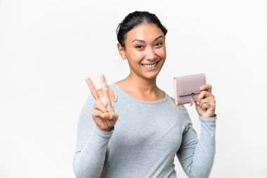 Young Uruguayan woman holding a wallet over isolated white background smiling and showing victory sign