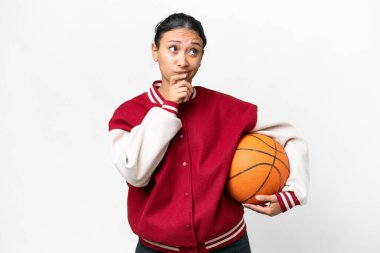 Young Uruguayan woman playing basketball over isolated wall  over isolated white background having doubts