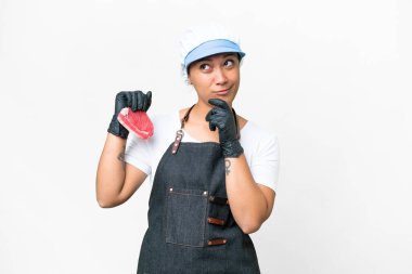 Butcher woman wearing an apron and serving fresh cut meat over isolated white background having doubts