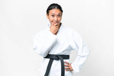 Young Uruguayan woman doing karate over isolated white background thinking