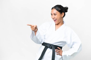 Young Uruguayan woman doing karate over isolated white background pointing finger to the side and presenting a product