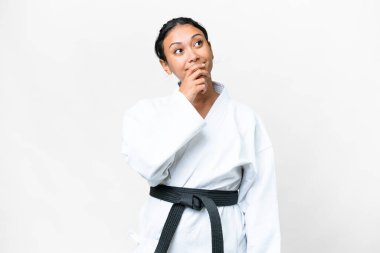 Young Uruguayan woman doing karate over isolated white background and looking up