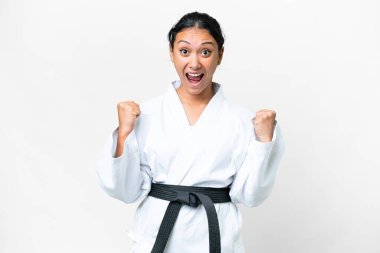 Young Uruguayan woman doing karate over isolated white background celebrating a victory in winner position