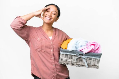 Young Uruguayan woman holding a clothes basket over isolated white background smiling a lot