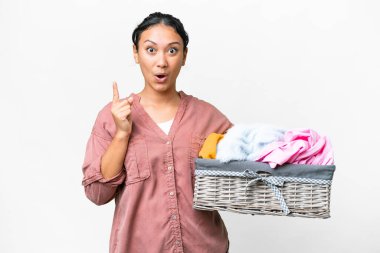 Young Uruguayan woman holding a clothes basket over isolated white background intending to realizes the solution while lifting a finger up