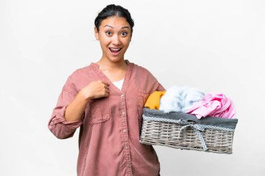 Young Uruguayan woman holding a clothes basket over isolated white background with surprise facial expression