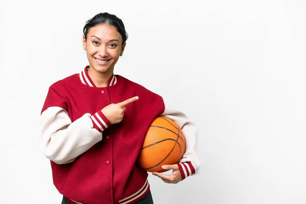 若いウルグアイの女性は 孤立した白い背景の上に孤立した壁の上にバスケットボールをプレイし 製品を提示する側面を指す — ストック写真