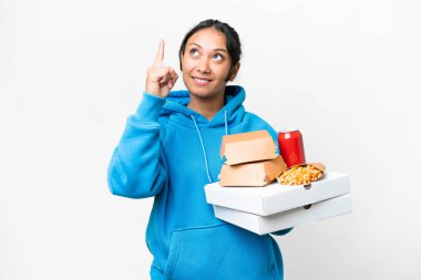 Young Uruguayan woman holding pizzas and burgers over isolated white background pointing up a great idea