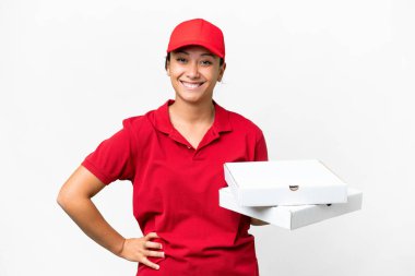 Pizza dağıtan kadın iş üniformalı izole edilmiş beyaz arka planda pizza kutuları alıyor kolları kalçasında ve gülümsüyor.