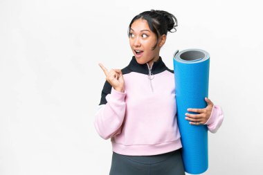 Genç sporcu kadın yoga derslerine giderken, beyaz arka planda bir paspas tutuyor. Çözümün farkına varmak için parmağını kaldırıyor.