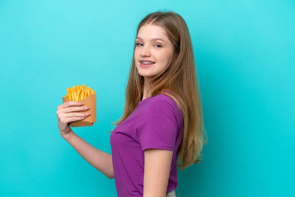 Неповнолітня Російська Дівчина Ловить Картоплю Фрі Ізольовану Синьому Фоні Посміхаючись — стокове фото