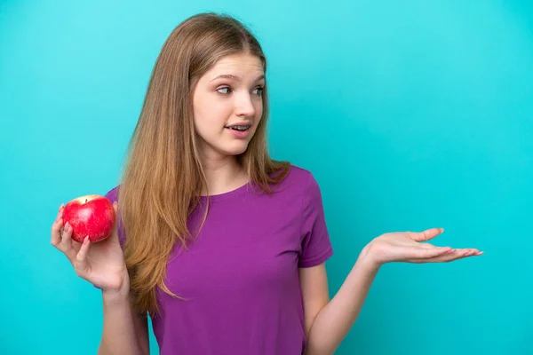 Young Caucasian Woman Isolated Blue Wall Holding Apple Happy Pleasant — Stock Photo, Image