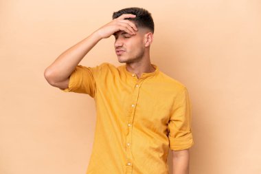 Young caucasian man isolated on beige background with headache