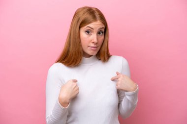 Pembe arka planda izole edilmiş genç kızıl saçlı kadın kendini işaret ediyor.