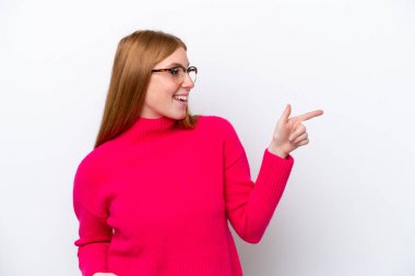 Young redhead woman isolated on white background pointing finger to the side and presenting a product