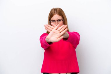 Beyaz arka planda izole edilmiş genç kızıl saçlı kadın bir hareketi durdurmak için elleriyle hareket yapıyor.