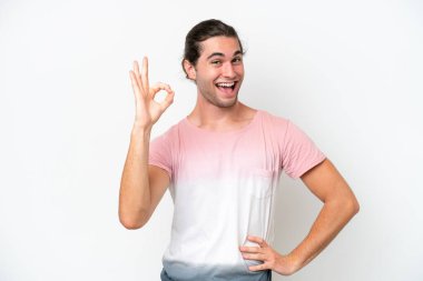 Beyaz arka planda izole edilmiş beyaz tenli yakışıklı adam parmaklarıyla tamam işareti gösteriyor.