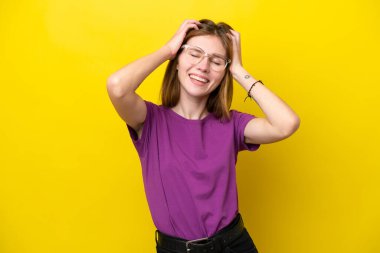 Sarı arka planda yalnız yaşayan genç İngiliz kadın gülüyor.