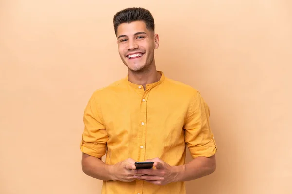 Beyazlı Genç Adam Bej Arka Planda Izole Edilmiş Cep Telefonuyla — Stok fotoğraf