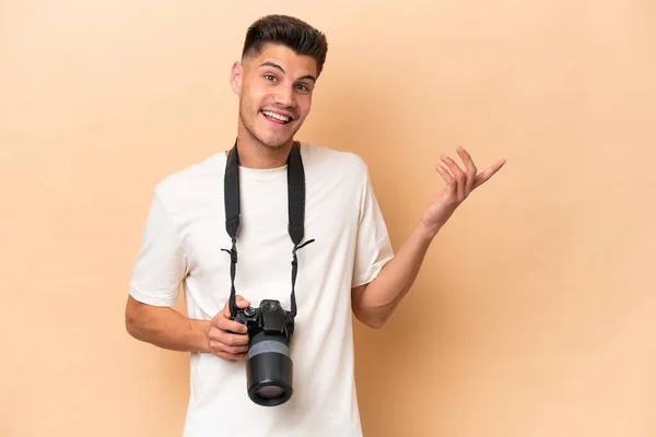 Young Photographer Caucasian Man Isolated Beige Background Extending Hands Side — Stock Photo, Image
