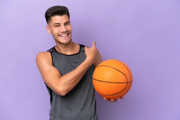young caucasian woman  basketball player man isolated on purple background pointing back
