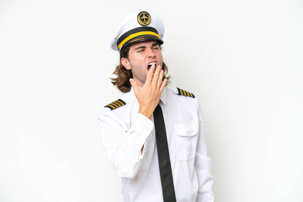handsome Airplane pilot isolated on white background yawning and covering wide open mouth with hand