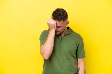 Sarı arka planda yalnız ve başı ağrıyan beyaz, yakışıklı bir genç.