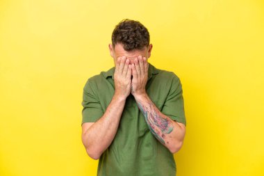 Sarı arka planda izole edilmiş, yorgun ve hasta bir ifadeyle genç, beyaz, yakışıklı bir adam.